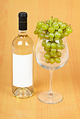 Image showing A bottle of wine, a large glass and grapes