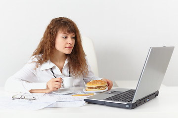 Image showing Girl, on workplace is going to eat hamburger