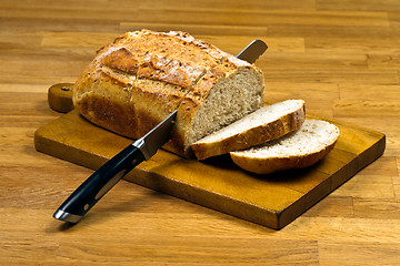 Image showing Wooden cutting board with white bread and knife