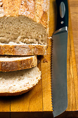 Image showing White bread and knife on wooden cutting board