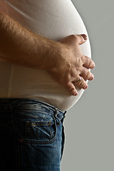 Image showing Overweight man with hand on belly