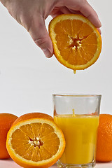 Image showing Orange juice dripping into glass from orange fruit