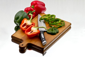 Image showing Bell peppers being cutted at wooden cutting board