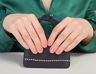 Image showing Female hands and black handbag