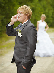 Image showing Groom has turned away from bride and speaks on phone