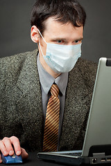 Image showing Man in medical mask works with laptop