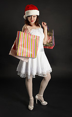 Image showing Beautiful girl in Christmas cap with gifts in hands