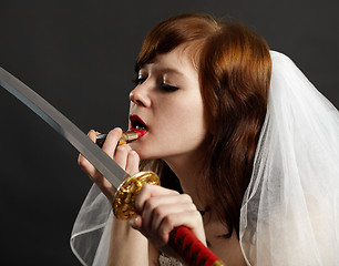 Image showing Bride lipstick using reflection in sword