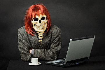 Image showing Man dressed as death sits at table with computer