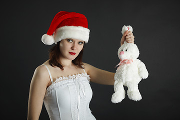 Image showing Woman in Christmas cap holds in hand a white rabbit