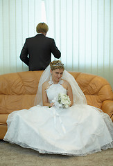 Image showing Bride sitting on couch, groom looks out window