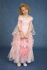 Image showing Little girl in pink dress stands on blue background