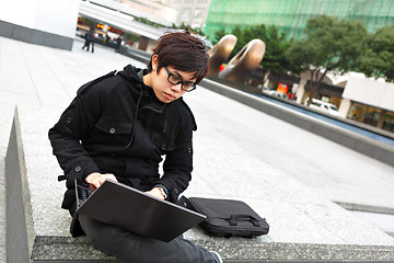 Image showing asian man using computer outdoor