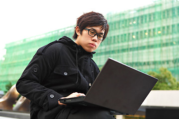 Image showing asian man using computer outdoor