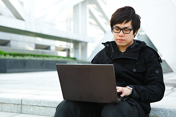 Image showing asian man using computer outdoor