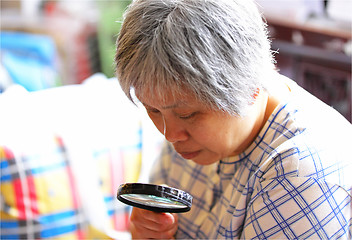 Image showing senior woman using magnifier