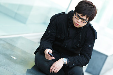 Image showing casual asian man texting on cell phone