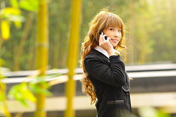 Image showing businesswoman talk phone beside trees