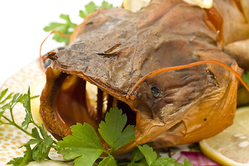 Image showing Closeup of Bloated sheatfish head with lemon and parsley