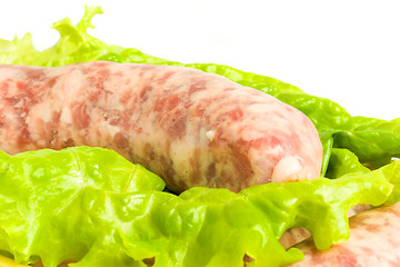 Image showing Closeup of one Uncooked Sausage on salad leaf