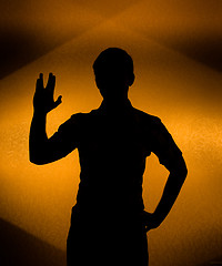 Image showing Back lit silhouette of man with raised hand