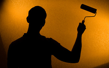 Image showing Back lit silhouette of man with paint-roller