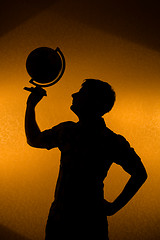 Image showing Back light - silhouette of man holding globe