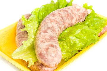 Image showing Uncooked Sausage on salad leaf