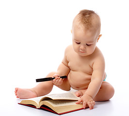 Image showing Little child play with book and magnifier