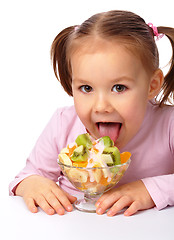 Image showing Little girl licks fruit salad