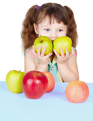 Image showing Girl playing with ripe apples sitting at table