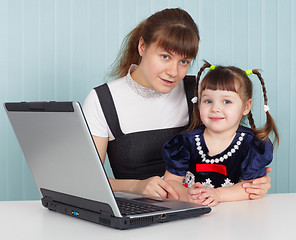 Image showing Mother and daughter sitting at table with computer