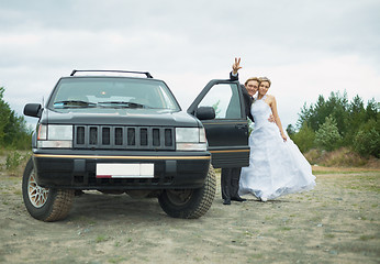 Image showing Happy newly-married couple says goodbye near car