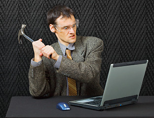 Image showing Comical person intends to break computer with hammer