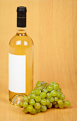 Image showing Still life - bottle of white wine and grapes on wooden surface