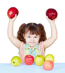 Image showing Girl playing with apples sitting at table