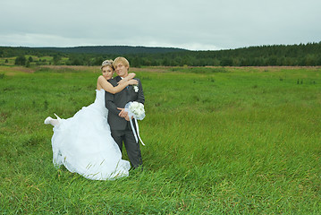 Image showing Bride and groom embrace on field