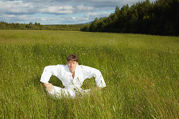 Image showing Young man sits in a grass