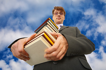 Image showing Man with big stack of books against sky