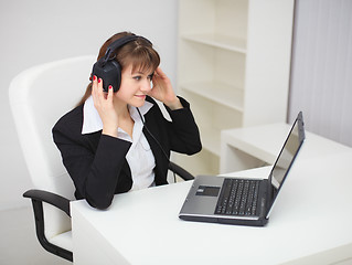 Image showing Woman listens to music by means of laptop and ear-phones
