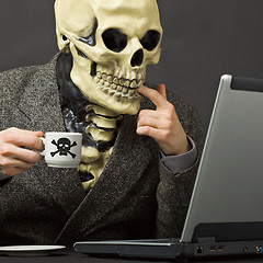 Image showing Skeleton drinks poisonous coffee at table with laptop