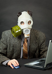 Image showing Amusing person has dressed gas mask and works with computer