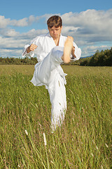 Image showing Young man in white kimono trains to beat foot