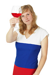 Image showing Girl looks at a glass of red wine on white