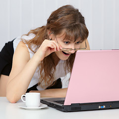 Image showing Young woman working with pink  laptop computer at table