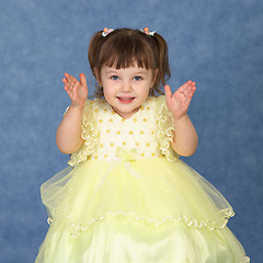 Image showing Little girl in beautiful dress claps his hands