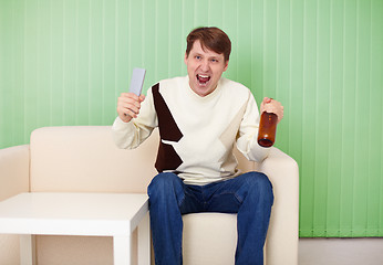 Image showing Football fan sitting at home on couch with TV