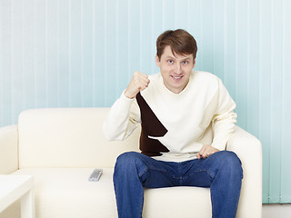 Image showing Guy sits on sofa and watches football on TV