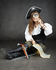 Image showing Girl pirate, and map with a magnifying glass on black background