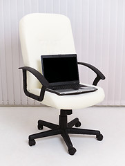 Image showing Black laptop sits in leather chair for manager